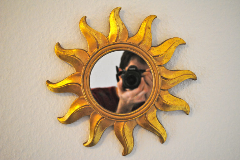 Autorretrato frente a un pequeño espejo en forma de sol